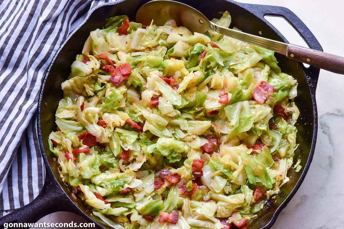 fried cabbage with bacon and chicken broth in a cast iron skillet