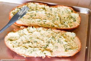 Step 3 how to make garlic bread, Cut the bread in half in lengthwise. Spread the butter mixture over the bread.