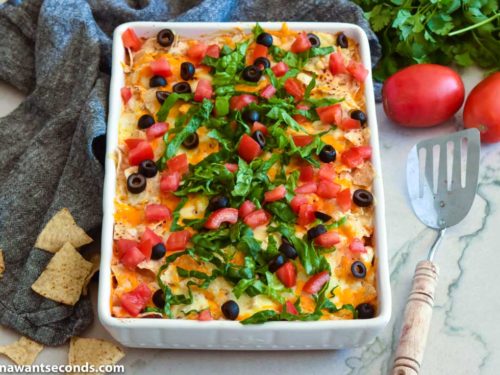 ground beef taco casserole topped with olives, lettuce, and tomatoes