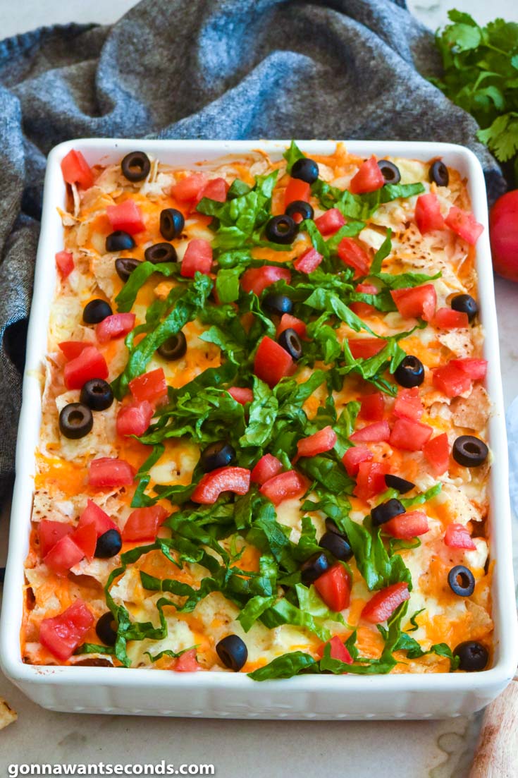 Taco casserole topped with olives, lettuce, and tomatoes