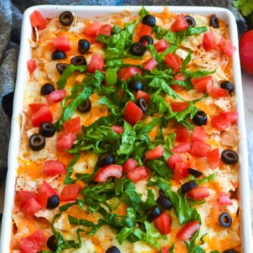 Taco casserole topped with olives, lettuce, and tomatoes