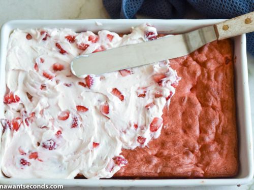 How to make strawberry jello cake, spreading the strawberry buttercream frosting on top of the cake