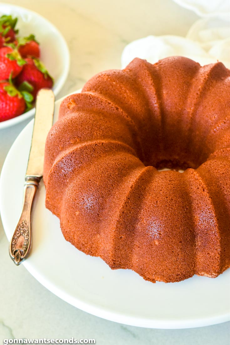 Old Fashioned Pound Cake on a plate with fresh strawberries on the side