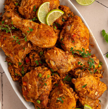 Arroz Con Pollo with lime wedges on top on a serving platter