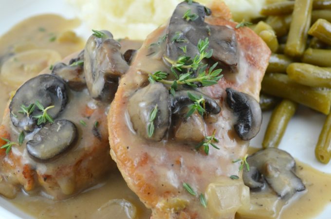Crock Pot Pork Chops smothered with gravy, topped with mushroom, with green beans on the side