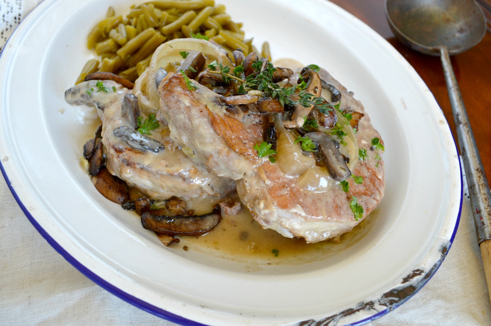 Crock Pot Pork Chops smothered with gravy, topped with mushroom, with green beans on the side