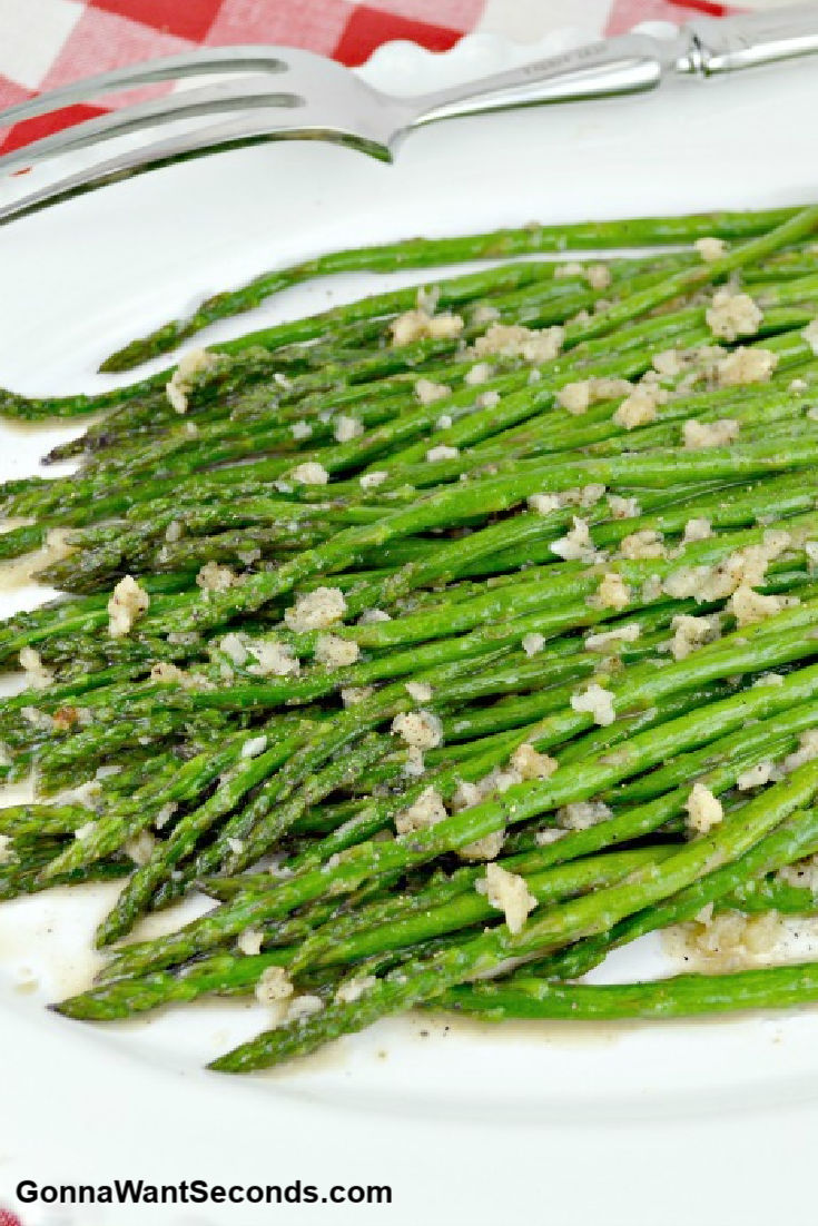 sauteed asparagus with garlic bits on top on a serving platter