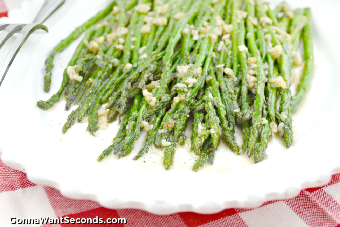 sauteed asparagus with garlic bits on top on a serving platter
