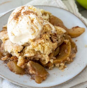 apple cobbler topped with vanilla ice cream, on a plate