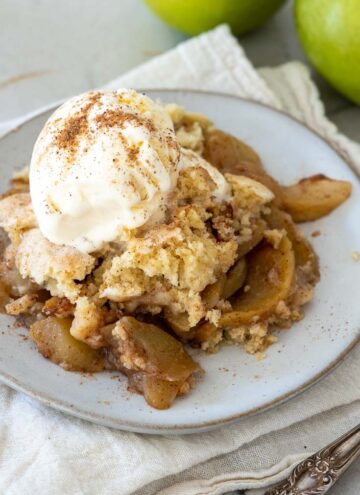 apple cobbler topped with vanilla ice cream, on a plate