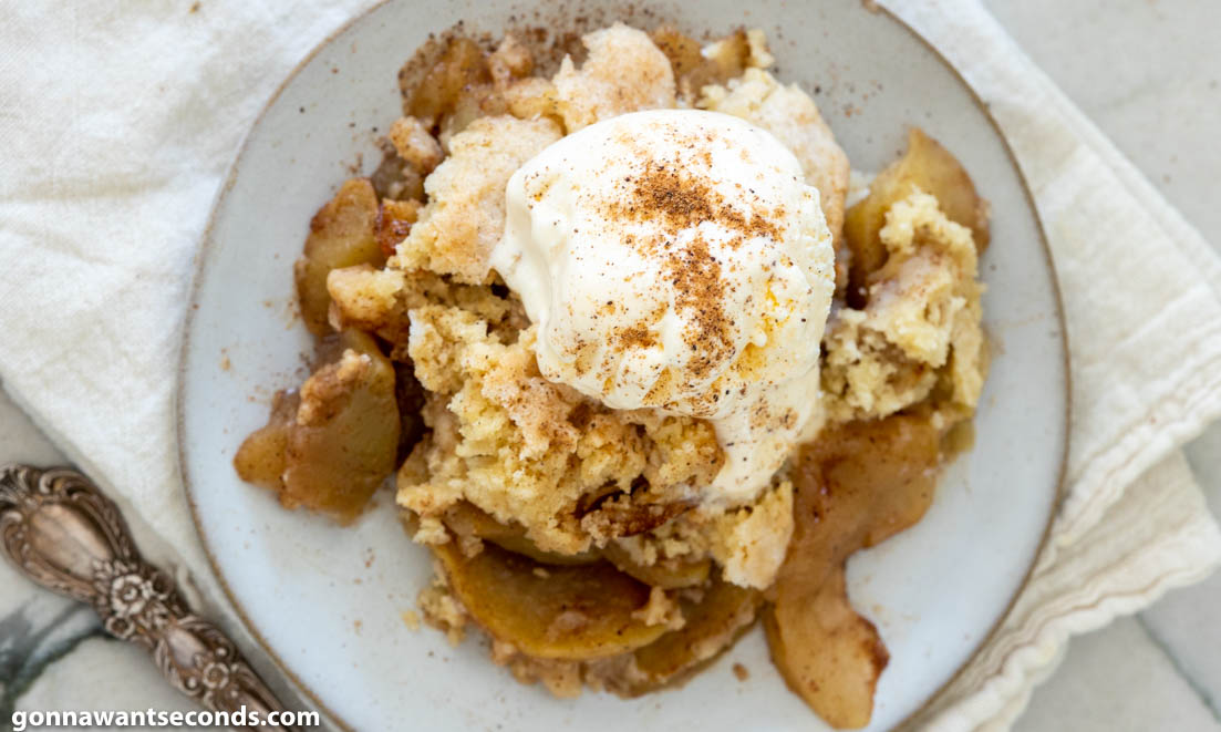 apple cobbler recipe topped with vanilla ice cream, on a plate