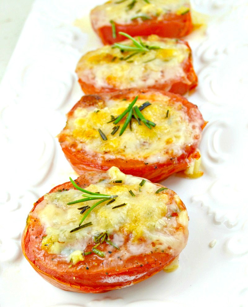 Baked Tomatoes topped with parmesan cheese, garnished with rosemary, arranged in a rectangular serving plate