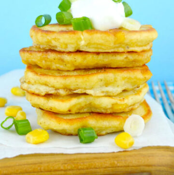 Southern corn cakes stack on top of each other with sour cream on tip