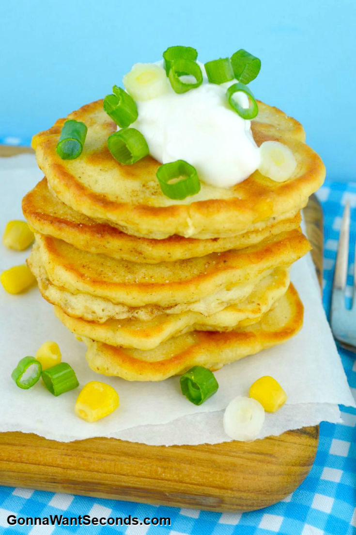 crispy corn cakes stack on top of each other with sour cream on tip