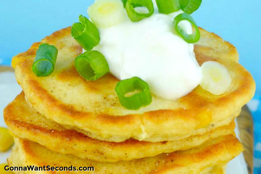 Southern fried corn cakes stack on top of each other with sour cream on tip