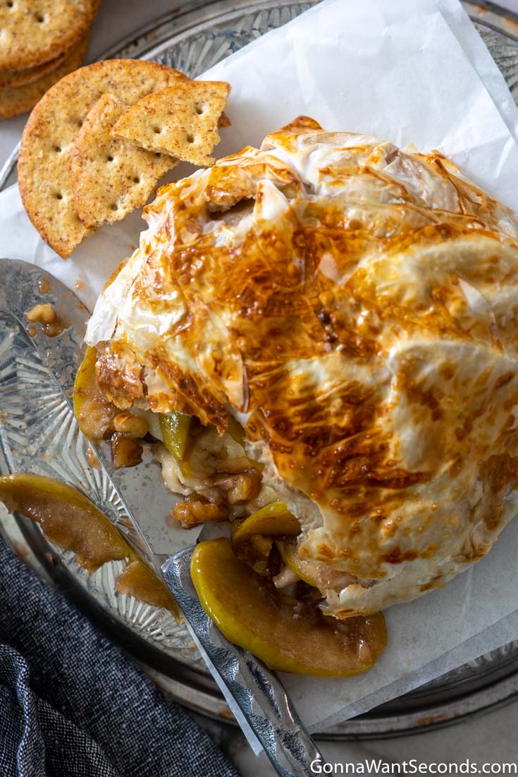 brie in puff pastry with cracker on the side, showing apples and walnuts inside