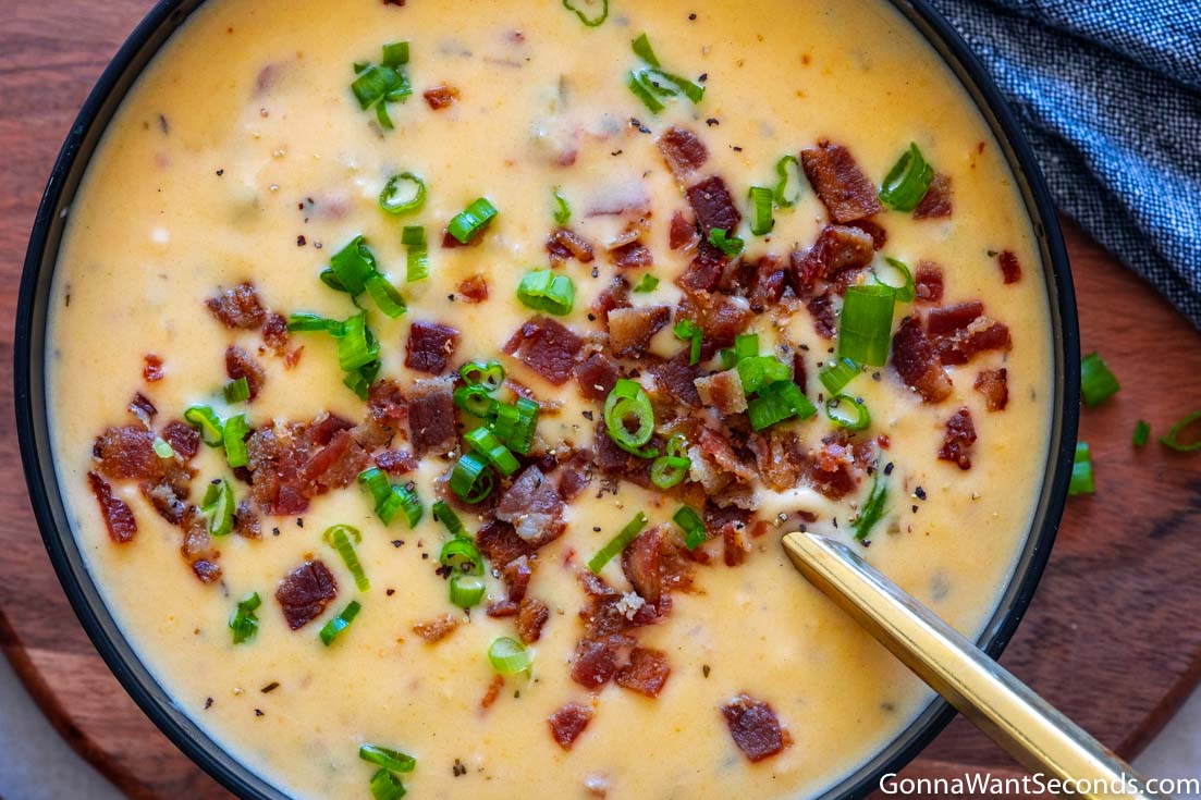 beer and cheddar cheese soup topped with bacon and green onions in a bowl