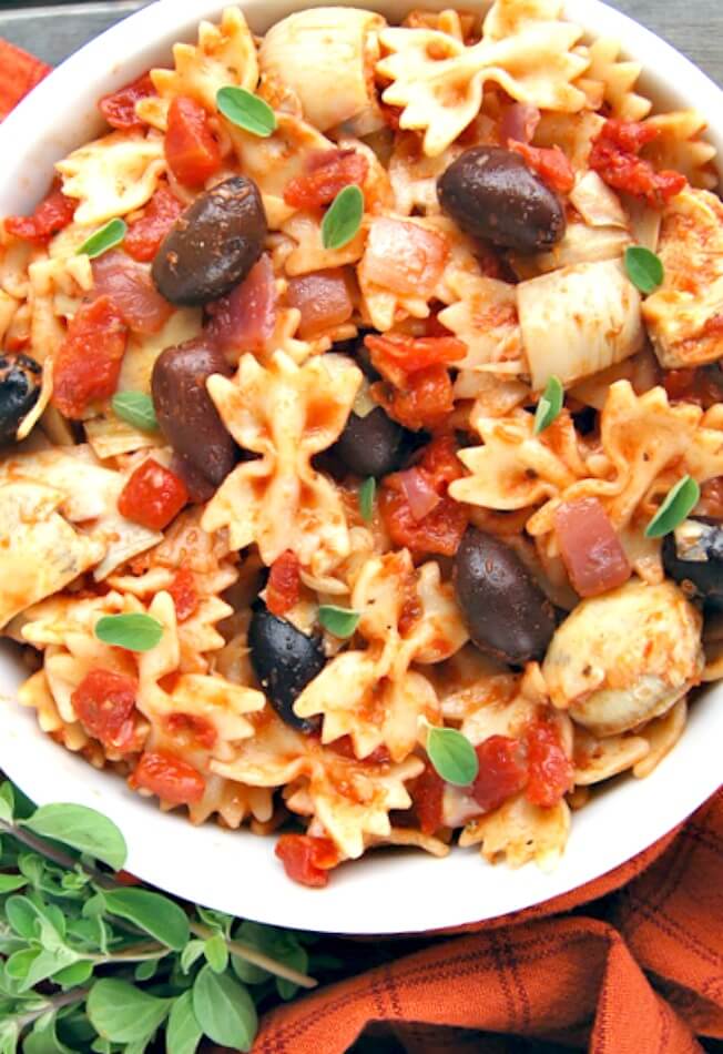 Greek Pasta ~ This quick and easy to put together recipe is a tantalizing combo of artichoke, sautéed onion and garlic, tomatoes, pasta, and, of course, a healthy portion of feta cheese. Can be made as a vegetarian entree or add chicken to make it a hearty Greek Pasta with Chicken.