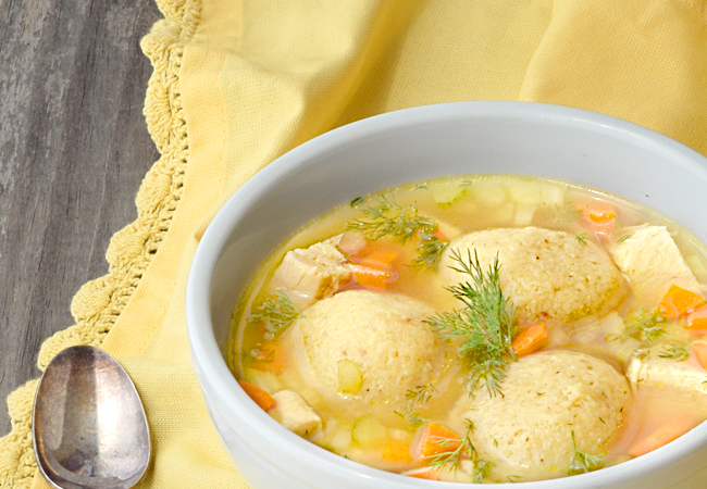 Matzo Ball Soup, garnished with fresh dill in a white soup bowl