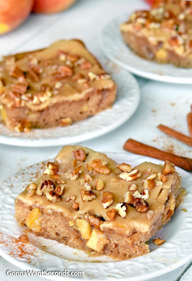 Two slices of Caramel Apple Sheet Cake topped with caramel icing and chopped nuts