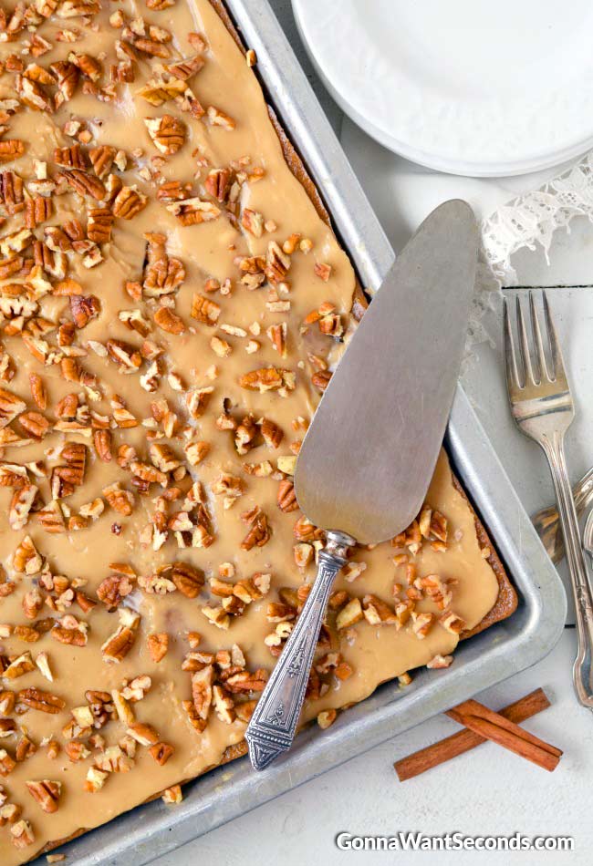 Caramel Apple Sheet Cake topped with caramel icing and chopped nuts in a baking pan