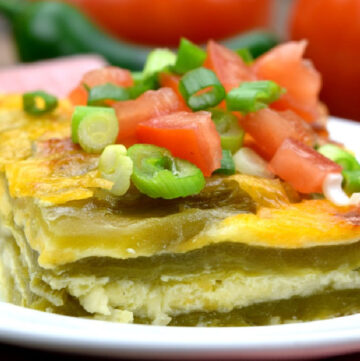 A slice of chili relleno casserole topped with tomatoes and green onions on a plate