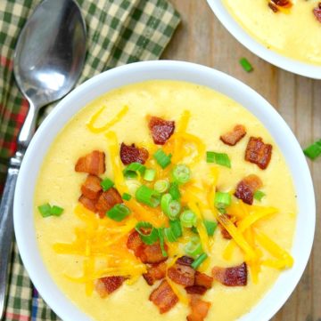 Easy Potato Soup topped with bacon bits, shredded cheese, and spring onions, in a white bowl.