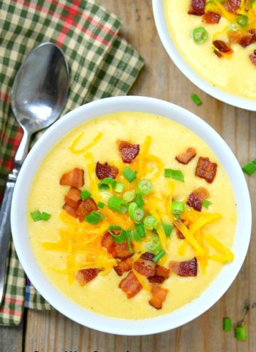 Easy Potato Soup topped with bacon bits, shredded cheese, and spring onions, in a white bowl.