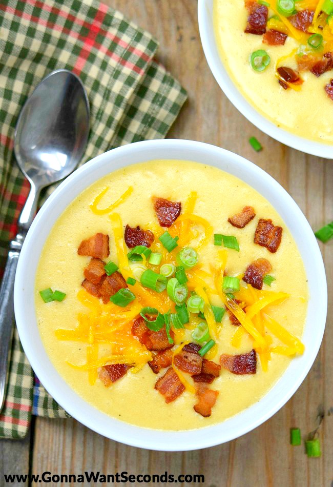 Easy Potato Soup topped with bacon bits, shredded cheese, and spring onions, in a white bowl. 