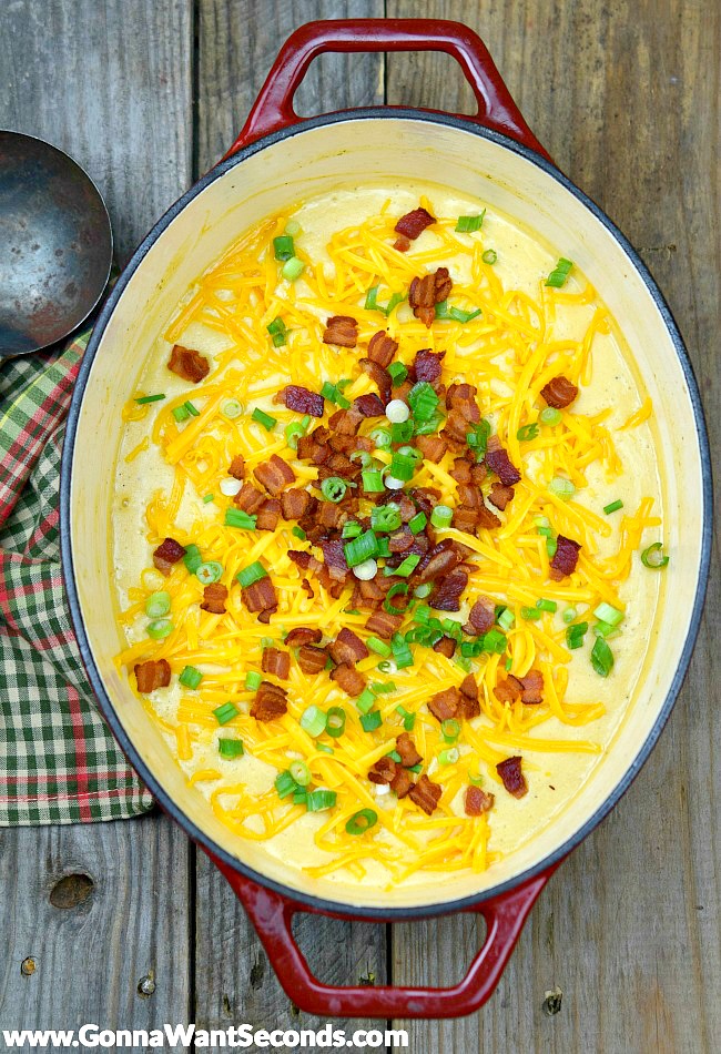 Easy Potato Soup topped with bacon bits, shredded cheese, and spring onions, in an oval dutch oven
