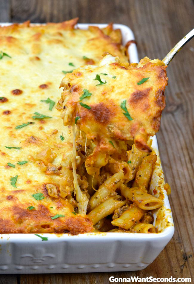 Scooping Baked Mostaccioli from a casserole dish