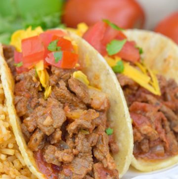 Carne Picada topped with cheese and tomatoes, in taco shells