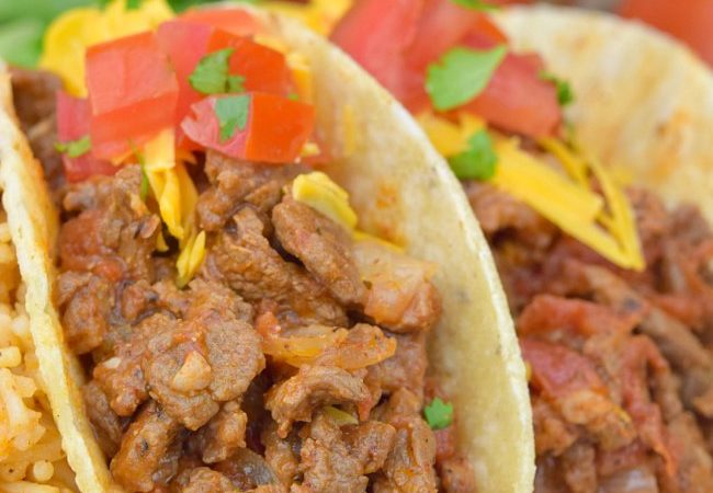 Carne Picada topped with cheese and tomatoes, in taco shells