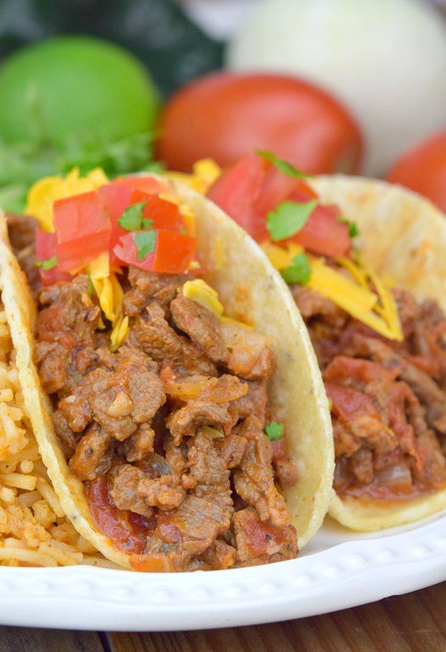 Carne Picada topped with cheese and tomatoes, in taco shells 