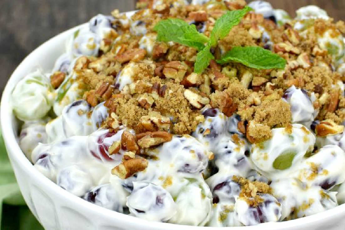 grape salad with cream cheese topped with crushed pecans in a bowl