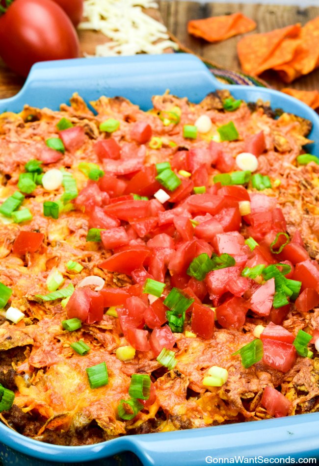 Easy Dorito Casserole topped with fresh tomatoes in a blue casserole dish