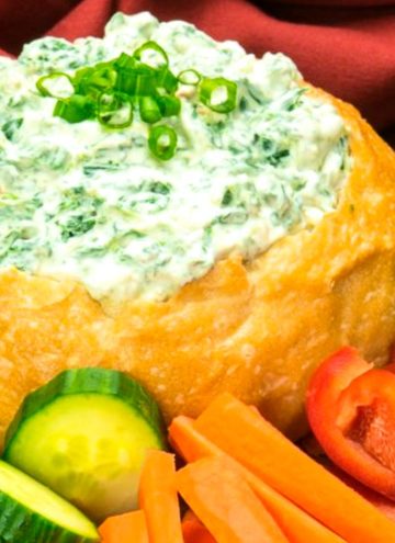 knorr spinach dip with water chestnuts in a bread bowl, with veggies around