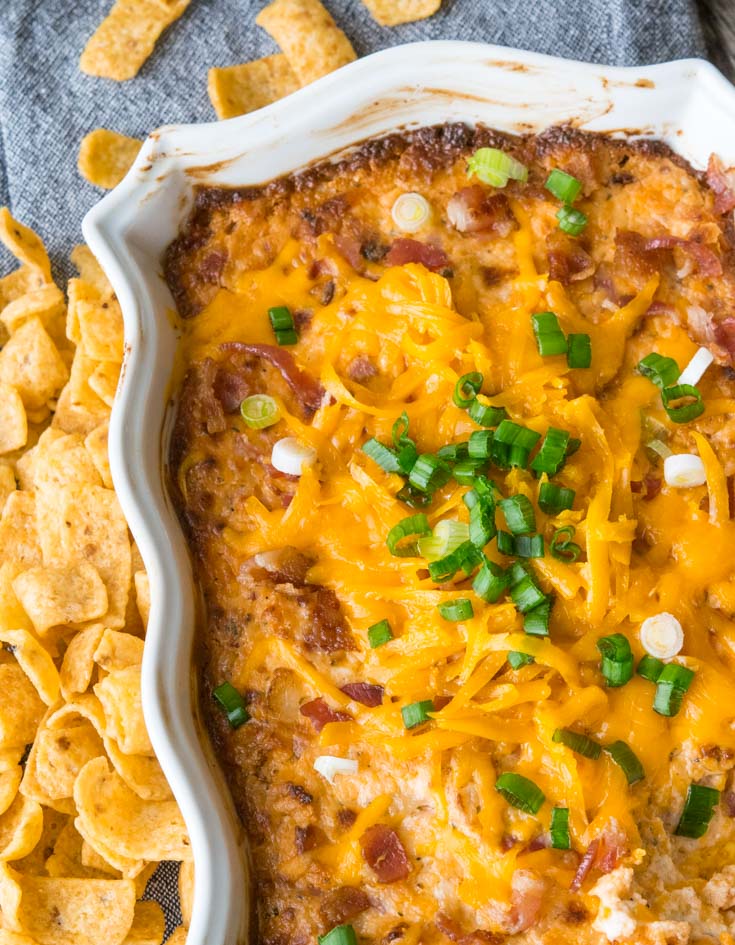 Crack Dip in a 2-quart baking dish topped with shredded cheese and green onions, with chips on the side 