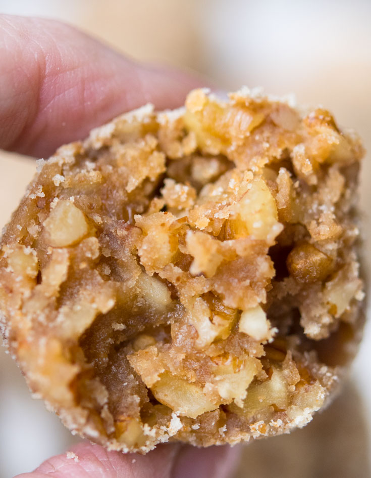 Easy Rum Balls are rich, boozy no bake bites with vanilla wafers, pecans, honey, rum, and bourbon—perfect for make-ahead gifting and parties too. #rumballs #nobake A half of Rum Balls held in hand