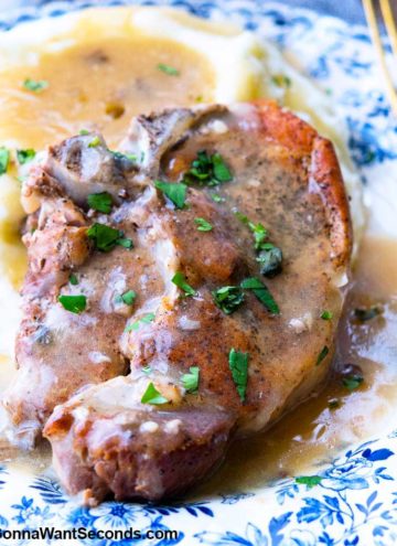 Instant pot pork chops and mashed potatoes, smothered with gravy, on a plate with fork