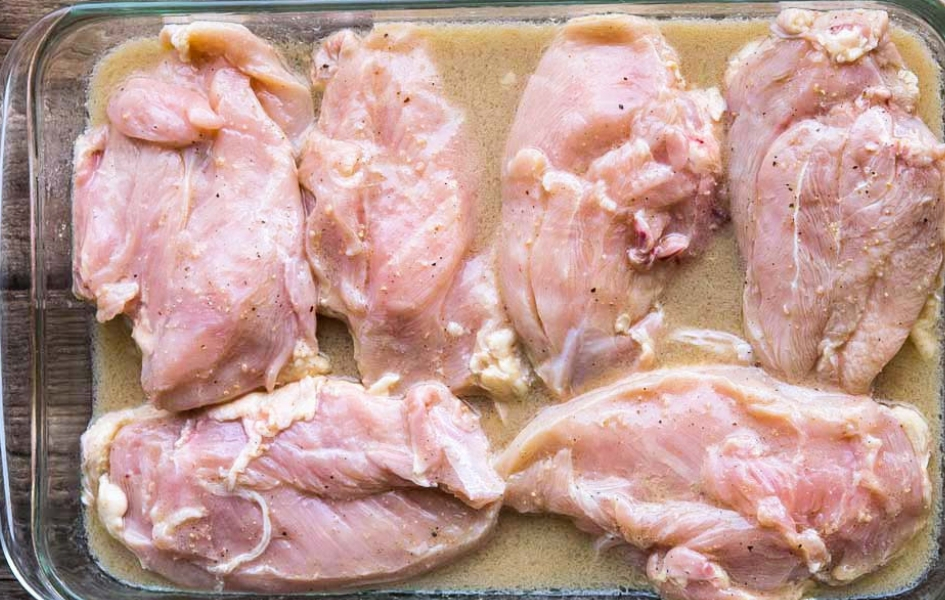 Chicken breasts with marinade in a baking dish. 
