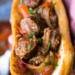 italian sausage and peppers in marinara sauce in an Italian sausage rolls, held in hand