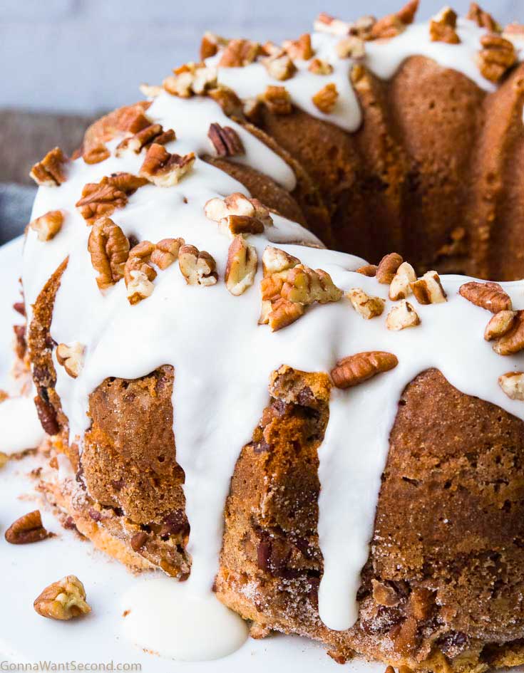 Sour cream coffee cake with glaze on top, garnished with chopped pecans