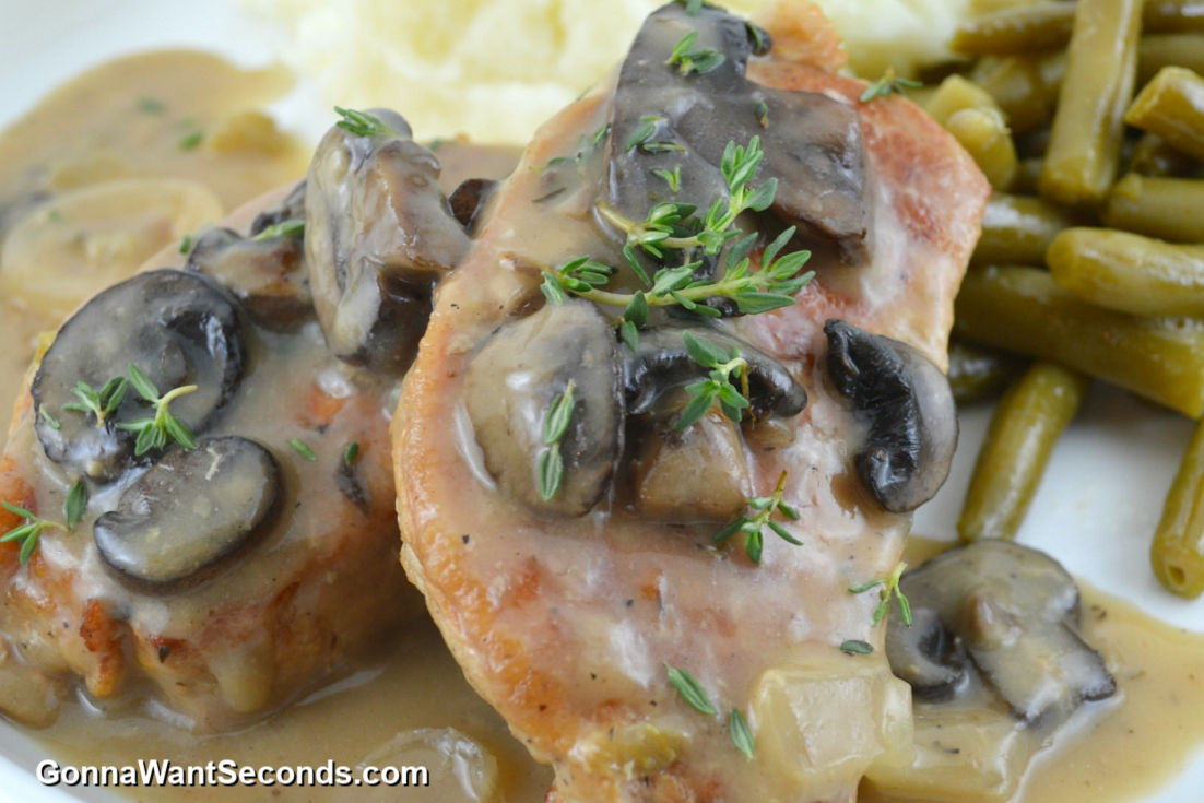 slow cooker pork chops and onions topped with mushrooms smothered in gravy