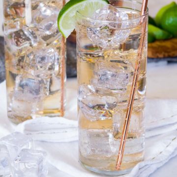 Two glasses of Gin and Ginger Ale with lime wedges