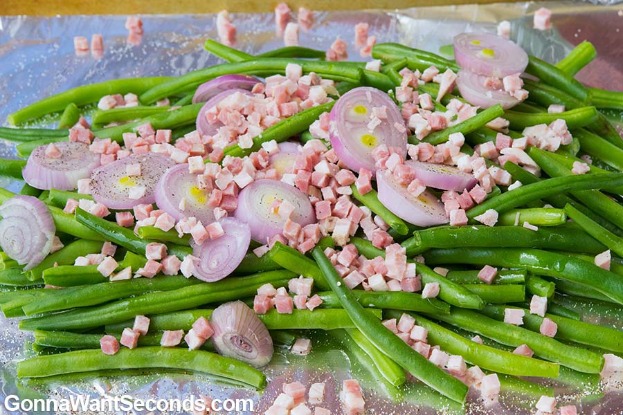 Prepared ingredients for Roasted Green Beans on an aluminum foil covered baking sheet