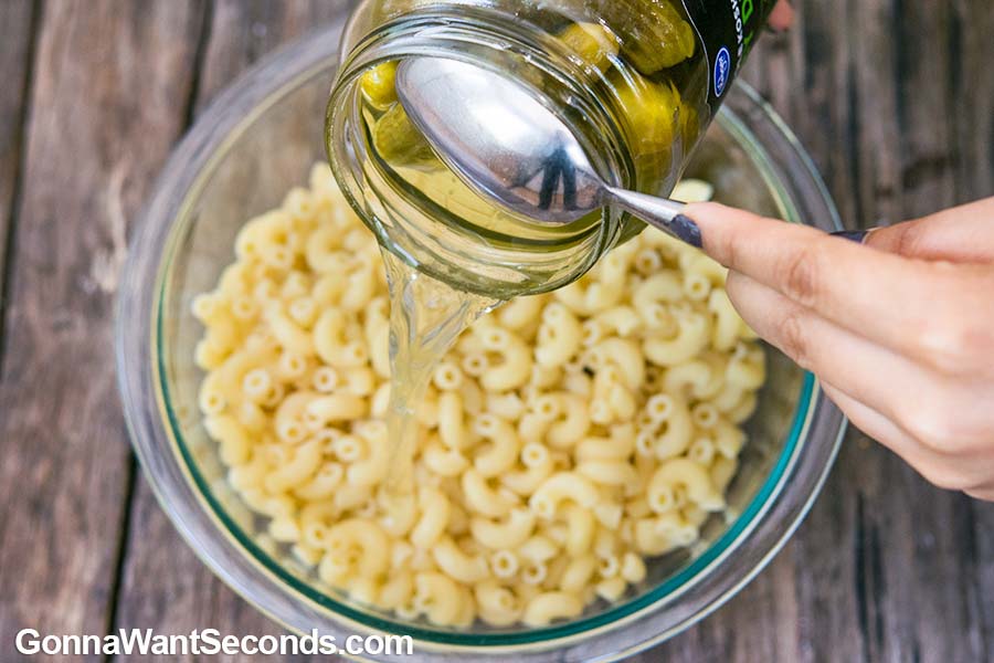 Pouring pickle juice to pasta to for Dill Pickle Pasta Salad