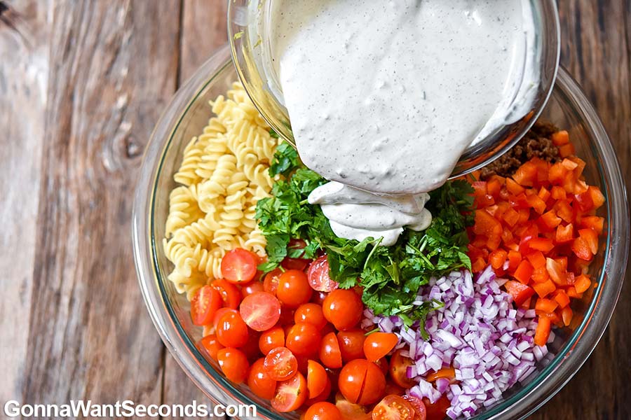 Pouring Taco Pasta Salad dressing on ingredients