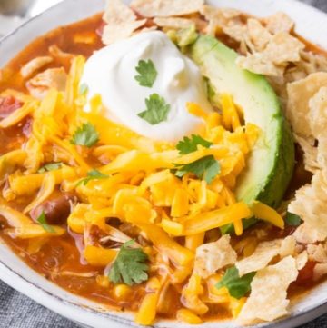 Chicken Taco Soup, topped with avocado, cheese, and sour cream, in a bowl
