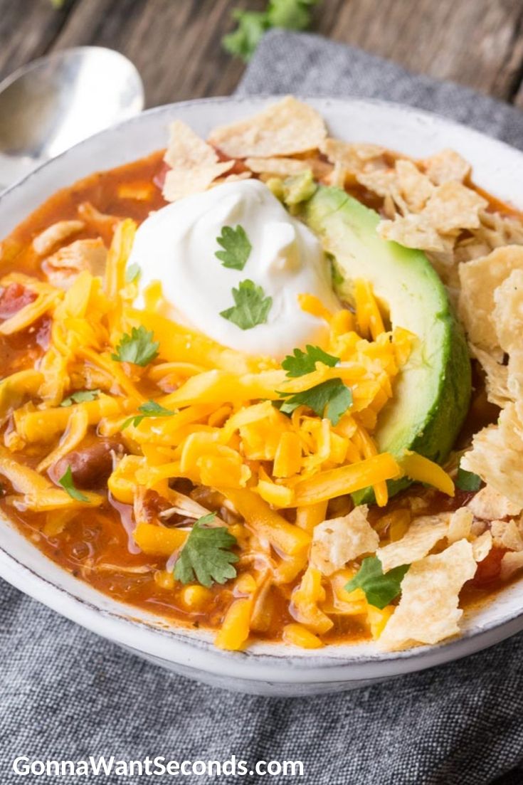 Chicken Taco Soup, topped with avocado, cheese, and sour cream, in a bowl